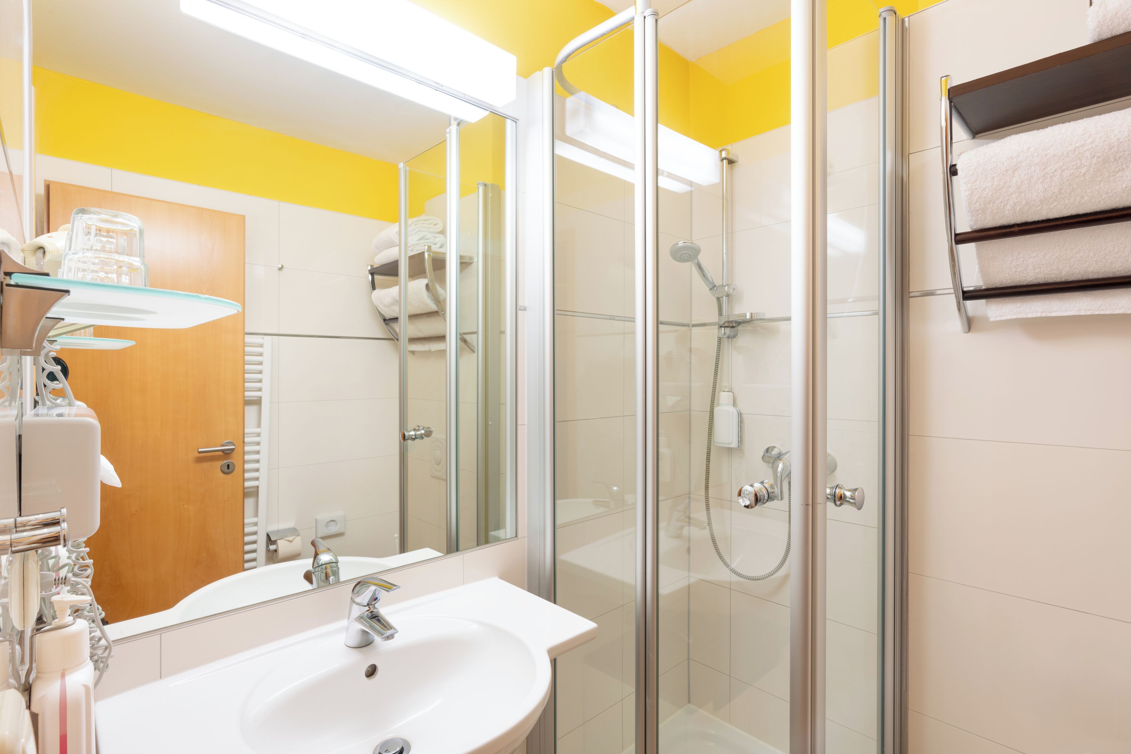 A bathroom with a glass-enclosed shower, a white sink, and a mirror.