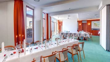 A conference room with a long table set for a meeting, equipped with chairs and a large screen.