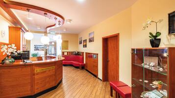 A reception area with a wooden reception desk, a red sofa, and a glass display cabinet with decorative items.