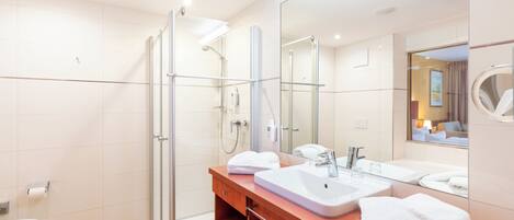 A modern bathroom with a glass shower enclosure, a wooden vanity with a sink, and a large mirror.