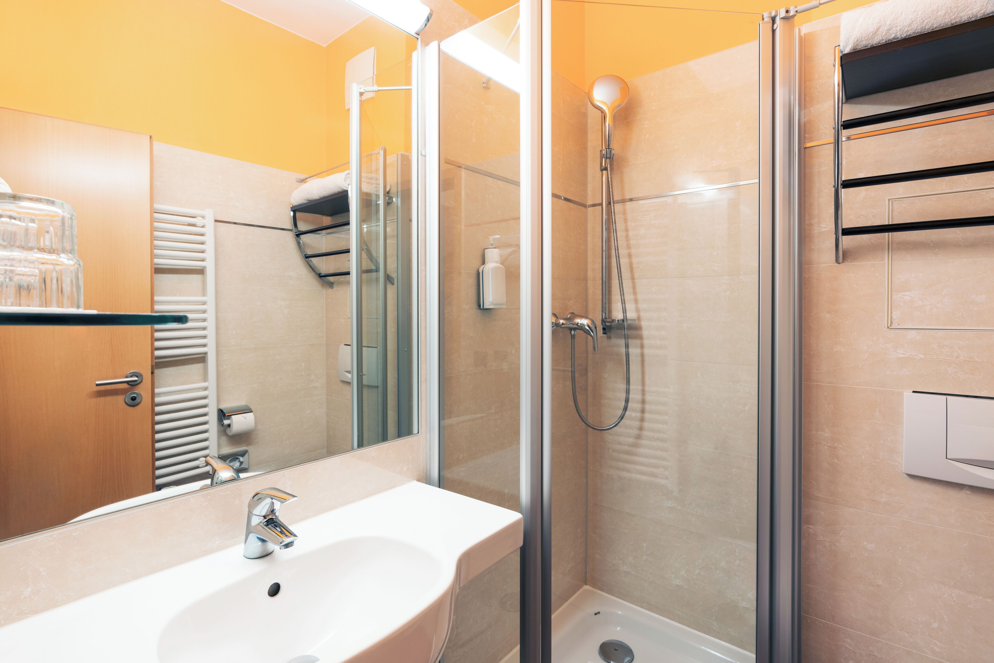 A bathroom with a glass-enclosed shower, a sink with a mirror, and a towel rack.