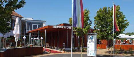 A hotel reception with a modern design, including a curved entrance and a sign indicating amenities like a restaurant and parking.