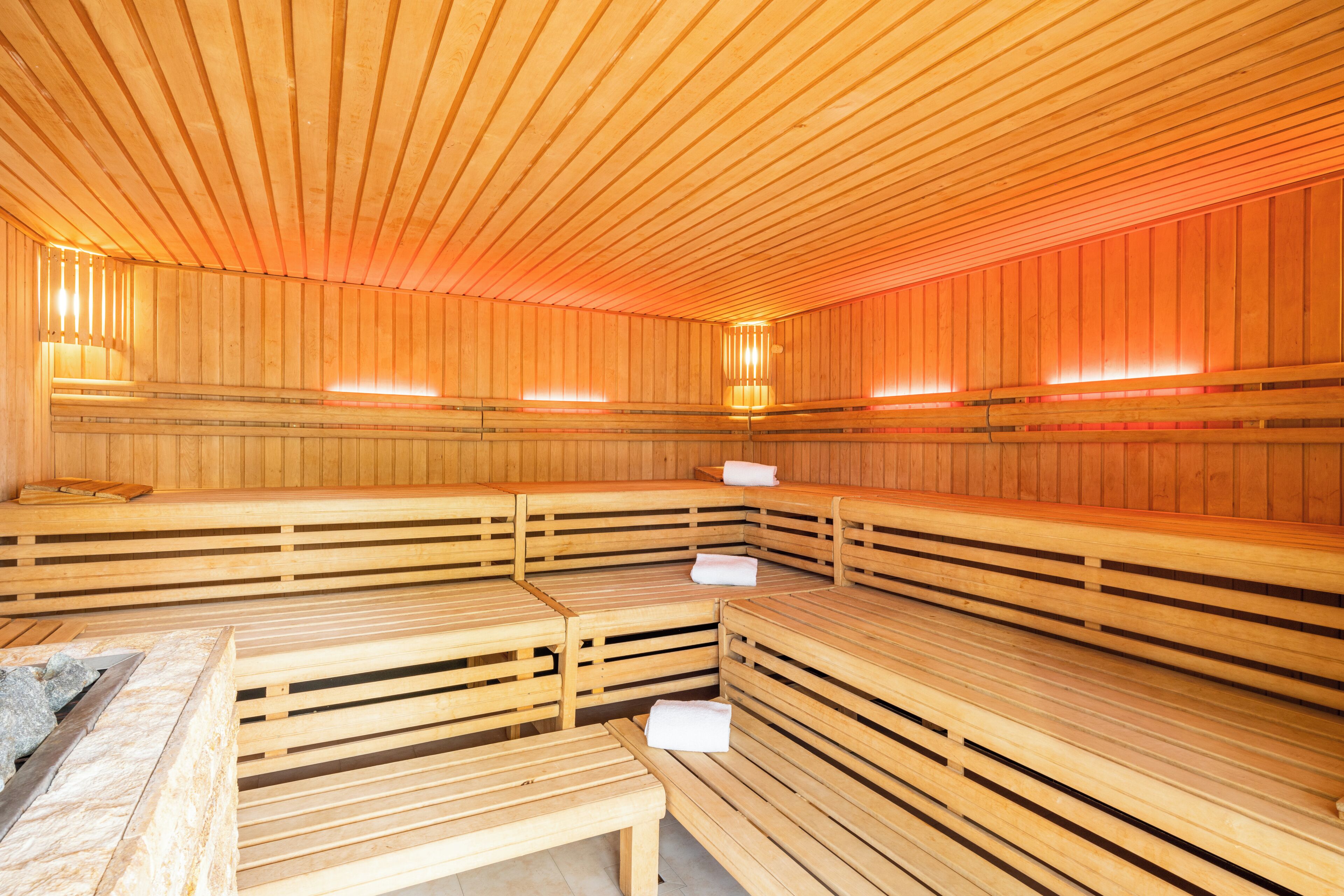 Una sauna con bancos de madera y un cuenco de piedra en primer plano.