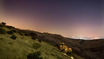 A house on a hillside with a starry night sky.