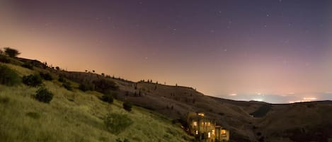 Una casa en una ladera bajo un cielo estrellado.