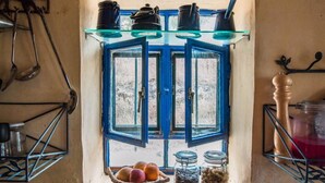 Une cuisine avec une fenêtre, un évier et des étagères remplies d’ustensiles de cuisine.