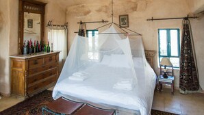 Une chambre à coucher avec un lit à baldaquin, une commode en bois, un miroir et un tapis à motifs.