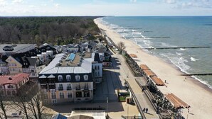 A coastal town with a beach, buildings with traditional architecture, and a promenade along the shore. - Apartamenty Sun&Snow Zachód Slonca (Mielno)