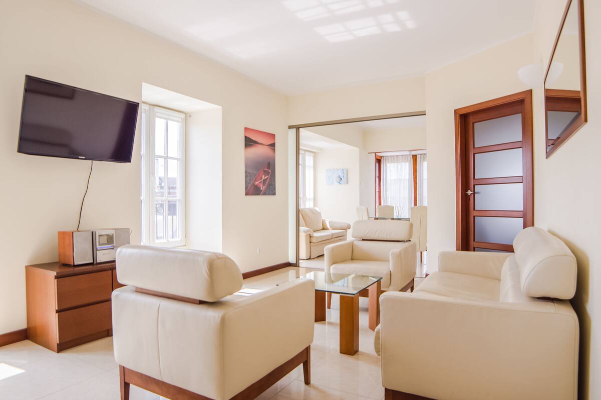 Ein modernes Wohnzimmer mit Flachbildfernseher, einer Couch, einem Couchtisch und einem TV-Schrank.