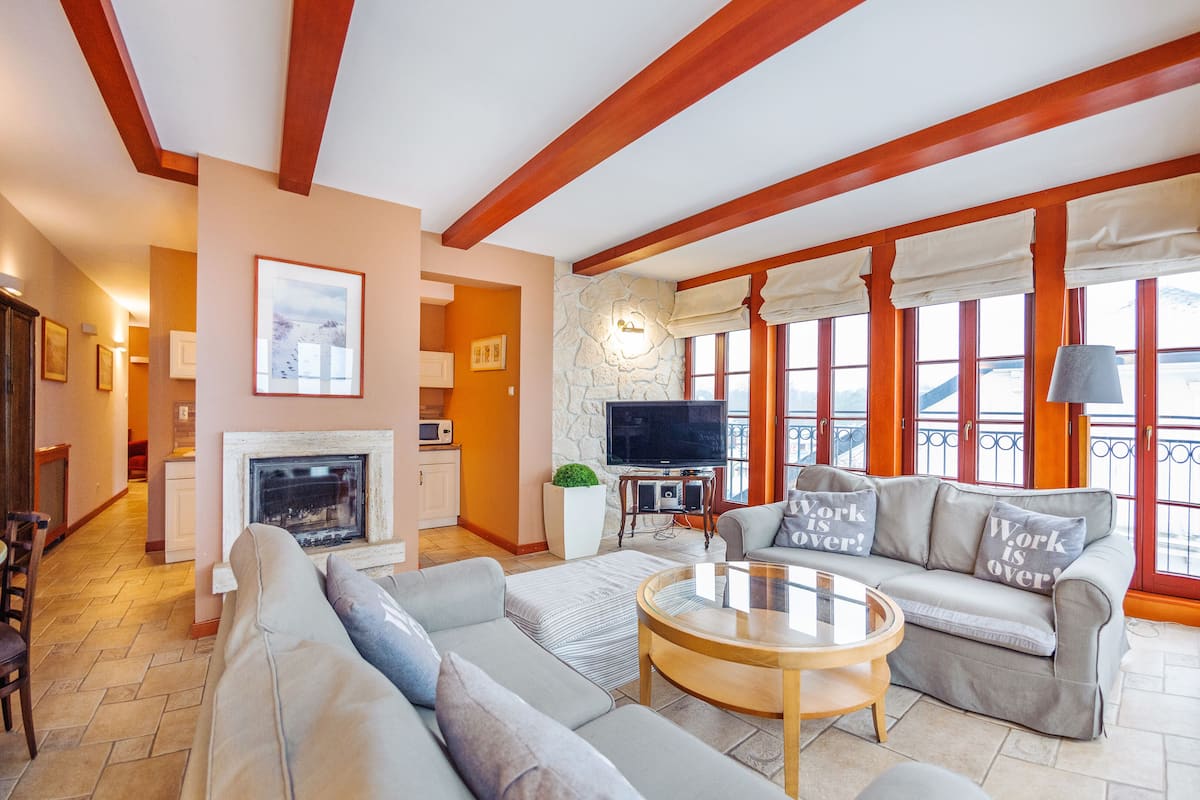 Ein Wohnzimmer mit Kamin, Fernseher und einer Couch mit Zierkissen.