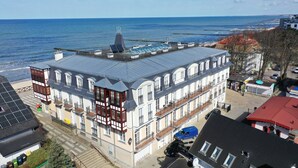 A multi-story building with a rooftop pool, located near a waterfront. - Apartamenty Sun&Snow Zachód Slonca (Mielno)