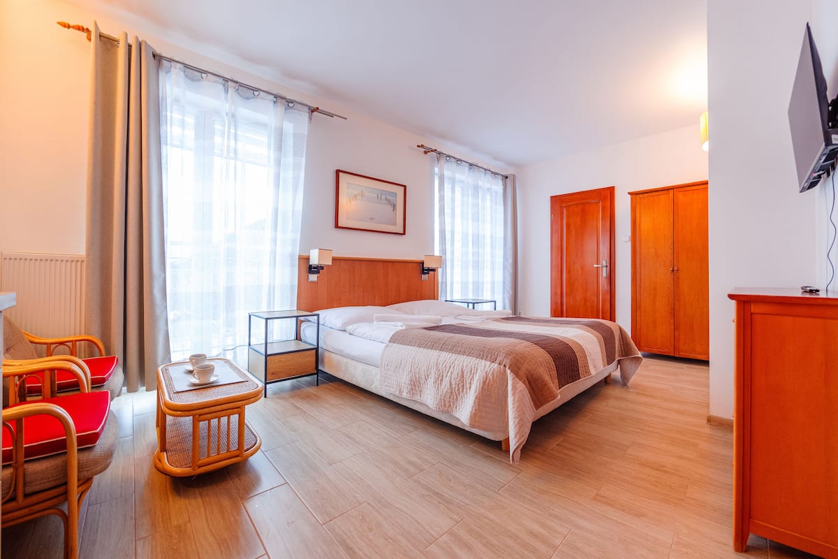 Ein Hotelzimmer mit Bett, Schreibtisch mit Stühlen, Fernseher und Kleiderschrank.