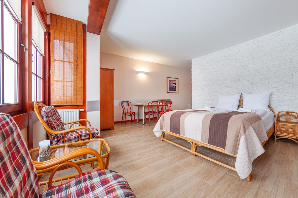 Ein Hotelzimmer mit einem Bett, zwei Korbstühlen, einem kleinen Tisch und einem Fernseher.