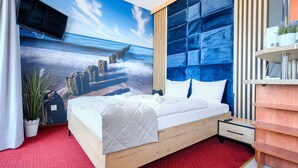 A modern bedroom with a large bed, a wooden headboard, a red carpet, and a wall mural of a coastal scene. - Apartamenty Sun&Snow Zachód Slonca (Mielno)