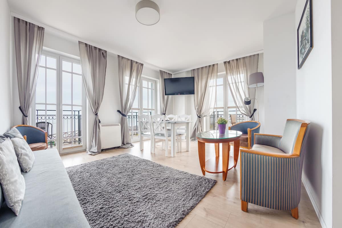 Ein modernes Wohnzimmer mit einer Couch, einem Sessel und einem Essbereich mit Tisch und Stühlen.
