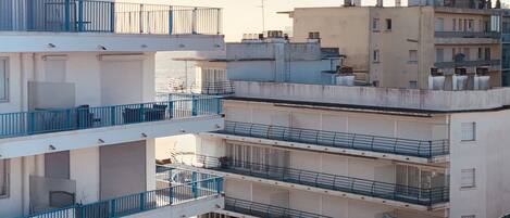 A multi-story residential building with balconies, a flat roof, and a clear sky.