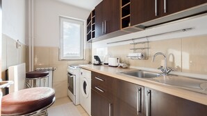 A modern kitchen with dark wooden cabinets, a stainless steel sink, and a built-in oven. - Studio 37 by MRG Apartments (Bucharest)