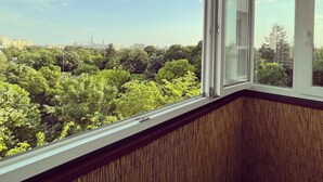 A room with a large window overlooking a dense green area with trees and buildings in the distance. - Studio 37 by MRG Apartments (Bucharest)