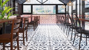 A restaurant with a high ceiling, large windows, and a patterned floor. - Tabalo Hostel Hanoi (Hanoi)