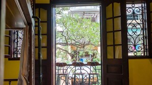 A room with a wooden floor, a bed, a window with a metal grill, and an air conditioning unit on the wall. - Tabalo Hostel Hanoi (Hanoi)