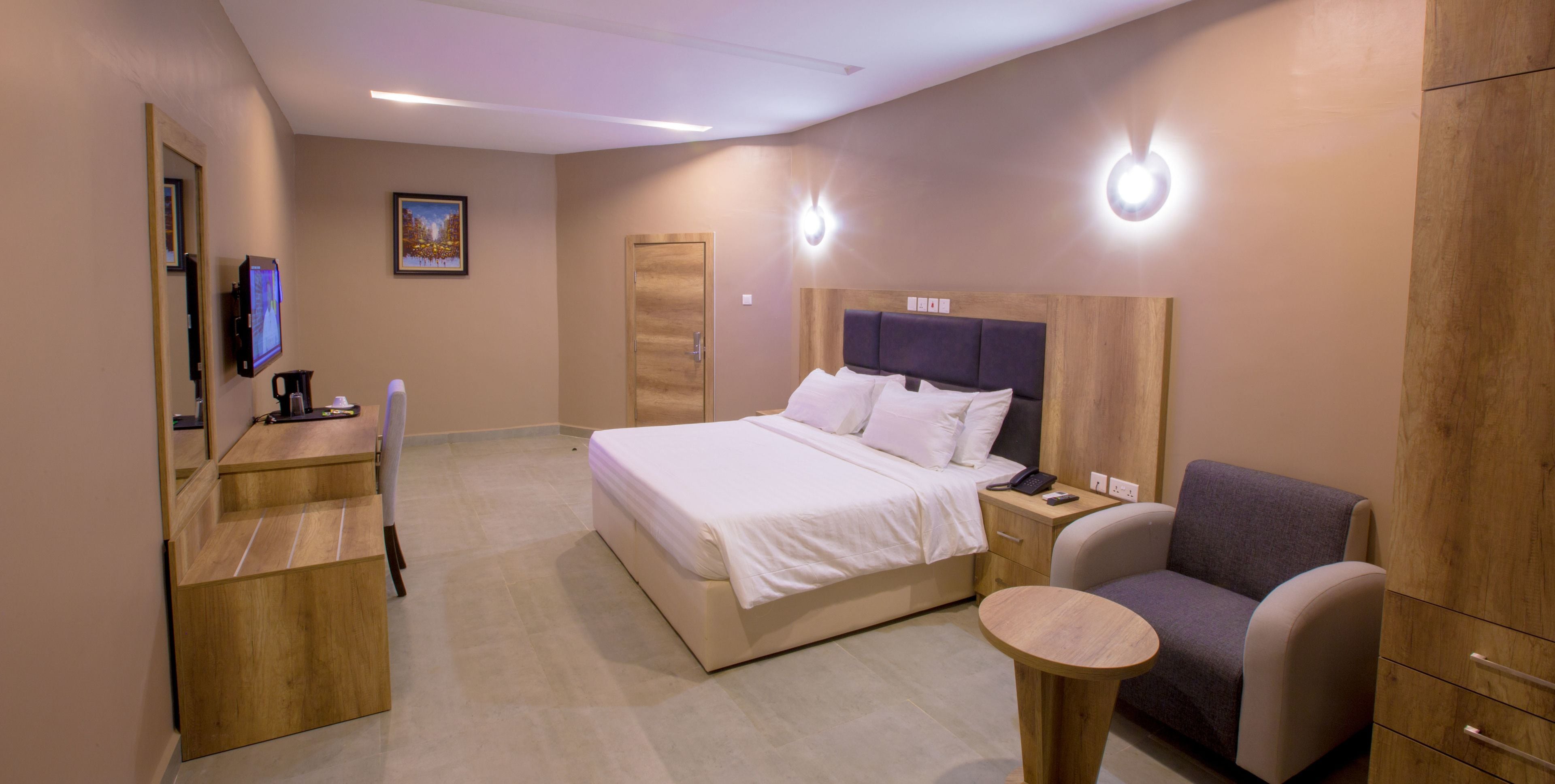 A hotel room with a bed, a desk, a chair, and a small table.