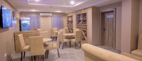 A hotel lobby with seating areas, a reception desk, a wall-mounted television, and a staff-only door.