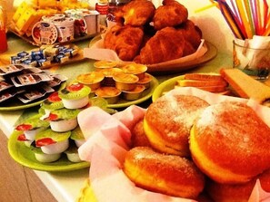 A buffet table with various food items including pastries, sandwiches, and desserts.