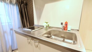 A kitchen with a stainless steel sink, a small countertop, and a cabinet with handles. - Elizabeth Garden Shinmachi (Osaka)