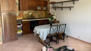 A kitchen with wooden cabinets, a stove, and a dining table with chairs. - Terra Luna house in the countryside (Mentana)