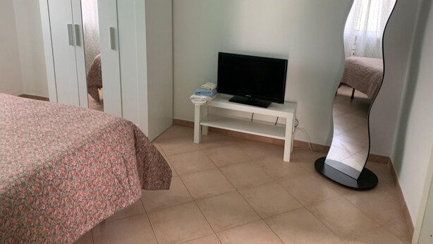 A bedroom with a bed, a TV on a stand, a wardrobe, and a mirror. - Terra Luna house in the countryside (Mentana)