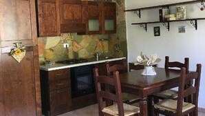 A kitchen with stone backsplash, wooden cabinets, and a dining area with a table and chairs. - Terra Luna house in the countryside (Mentana)