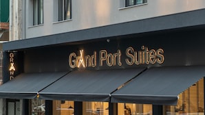 Un letrero de hotel con el nombre 'Grand Port Suites' iluminado con luces de neón.