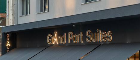 Un letrero de hotel con el nombre 'Grand Port Suites' iluminado con luces de neón.