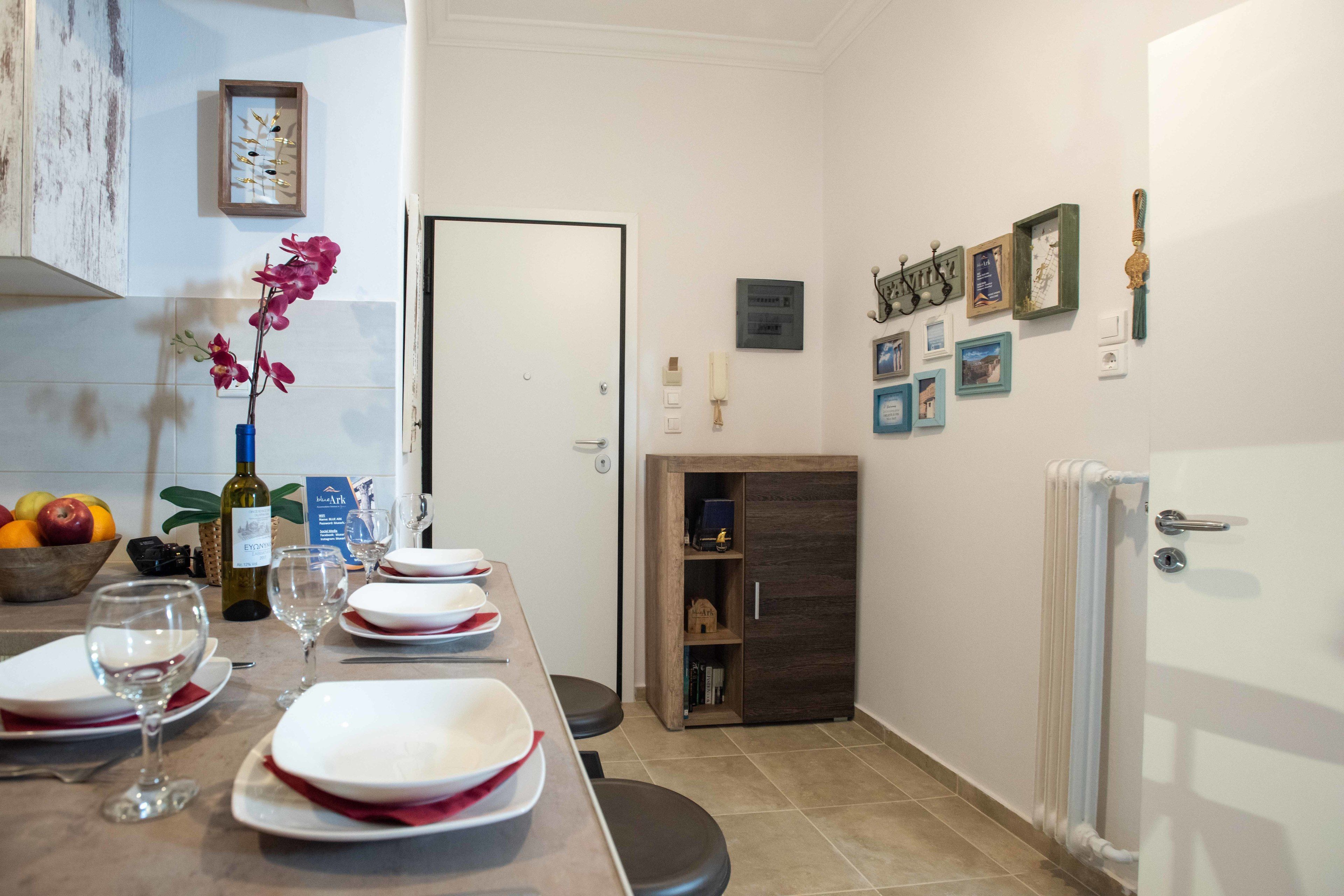 A dining area with a table set for four, a vase with flowers, and a fruit bowl.