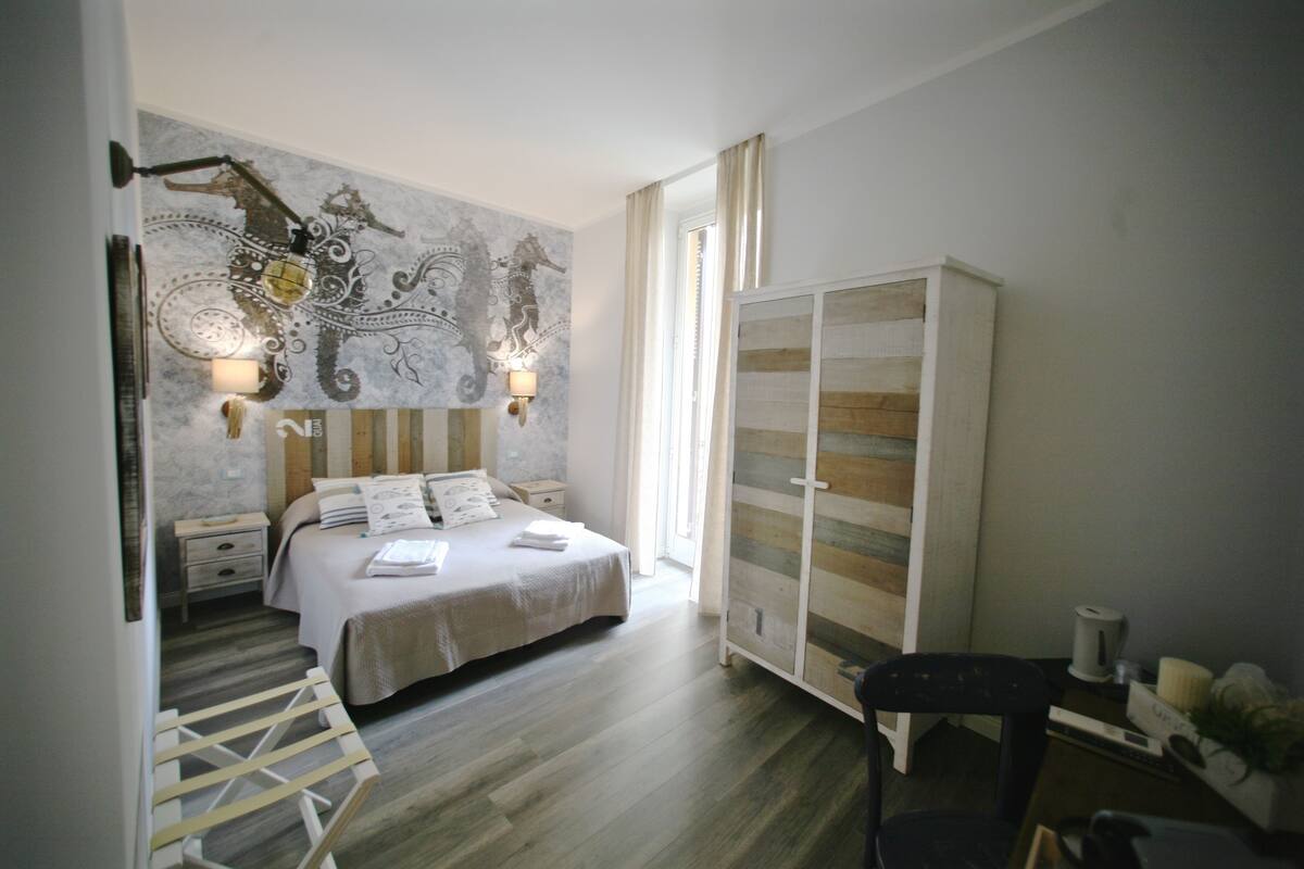 Een slaapkamer met een bed, nachtkastjes, een garderobe en een stoel.