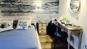 Une chambre à coucher ornée d’une fresque représentant des oiseaux volant au-dessus de l’eau, un lit avec des coussins assortis, un bureau avec un miroir et une commode.