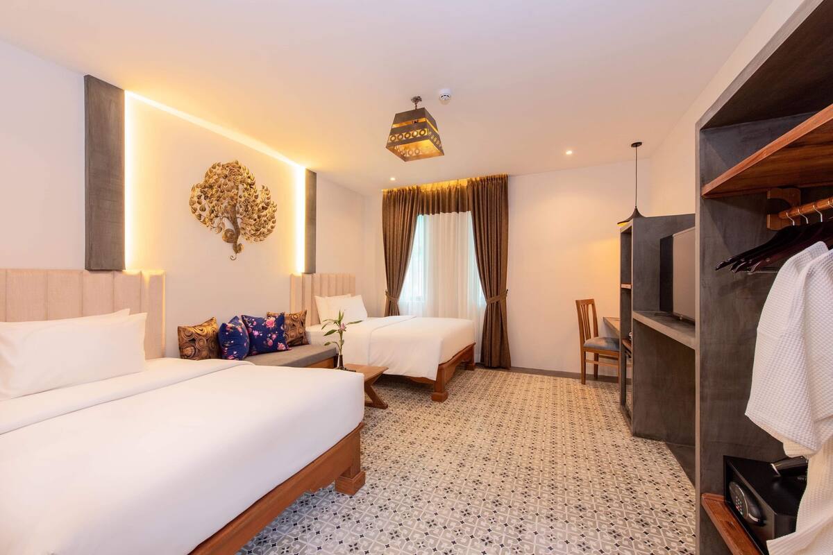 Une chambre d’hôtel avec deux lits, un coin salon, une armoire et un téléviseur.