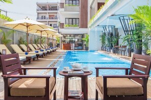 A poolside area with lounge chairs and umbrellas, a pool, and a bar area with seating. - Siem Reap Palace Hotel & Spa (Siem Reap)