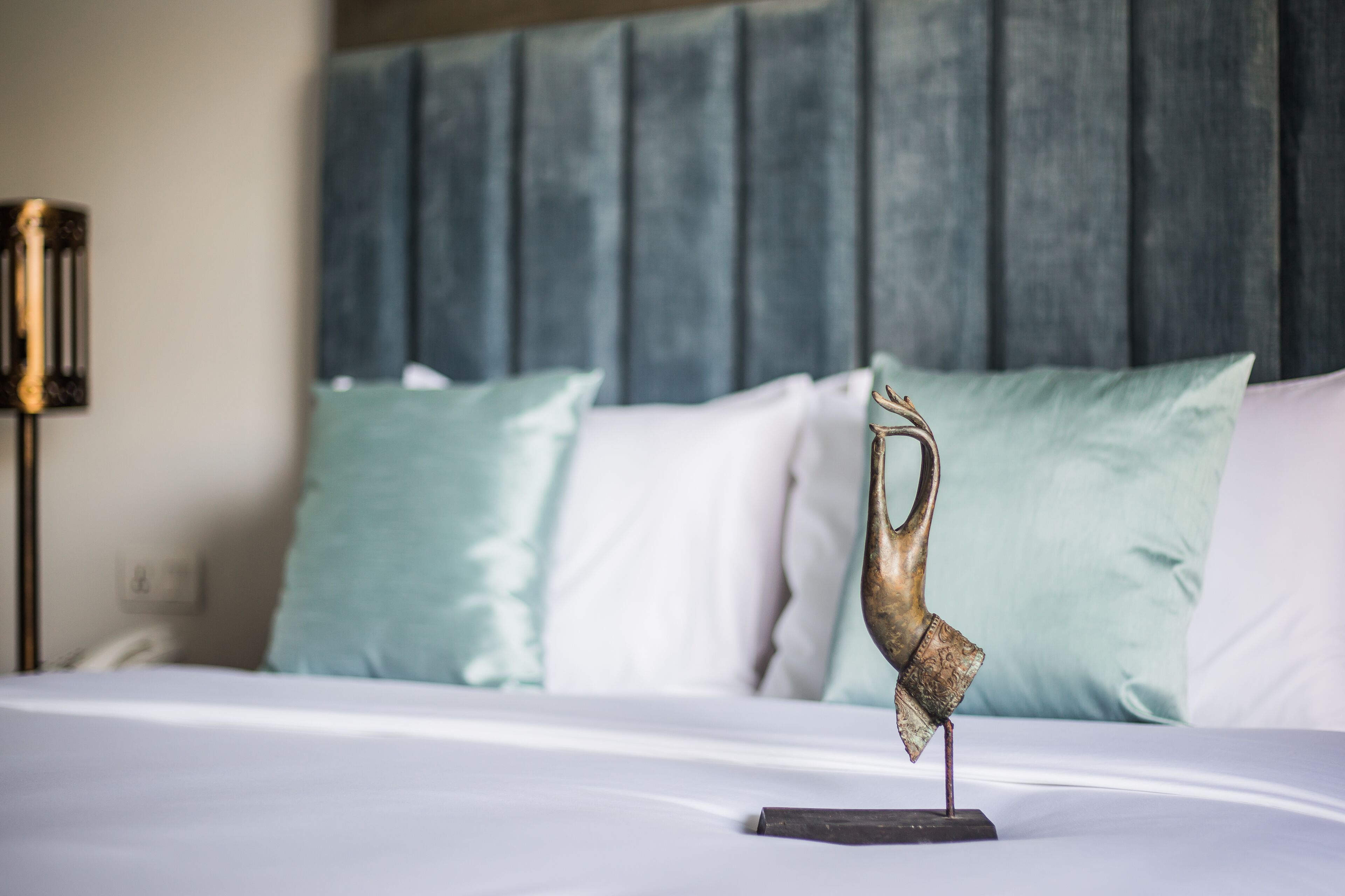 A bed with a decorative antler sculpture on a stand, a headboard, and two pillows.