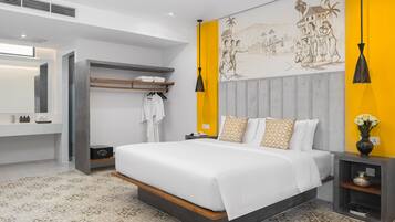 Una habitación de hotel moderna con una cama grande, una mesita de noche, un armario y un baño con espejo y toallero.