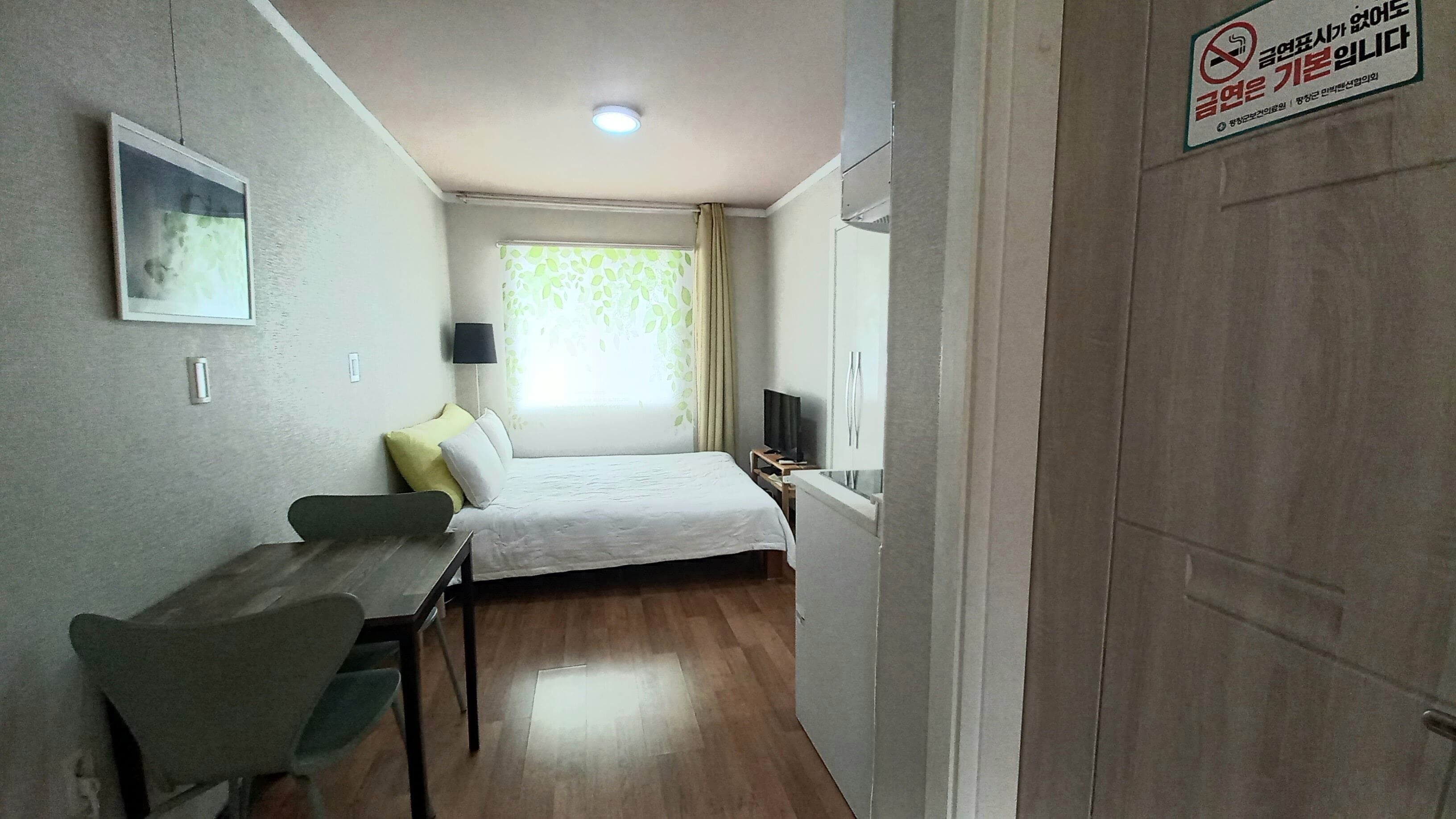 A hotel room with a bed, a desk, a chair, a television, and a window with curtains.