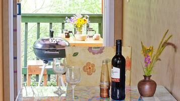 A table with a bottle of wine, a glass, a mug, and a vase with flowers.