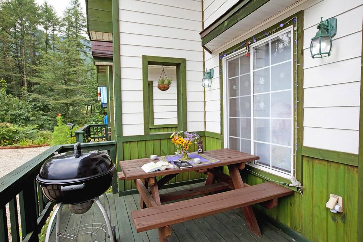 A wooden deck with a barbecue grill, picnic table, and hanging planter.