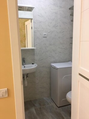 A small bathroom with a toilet, sink, and a mirror above the sink. - Kat Green Apartment (Odesa)
