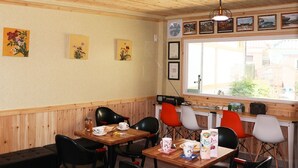 Un espace repas avec des lambris en bois, une fenêtre offrant une vue agréable et plusieurs tables accompagnées de chaises.
