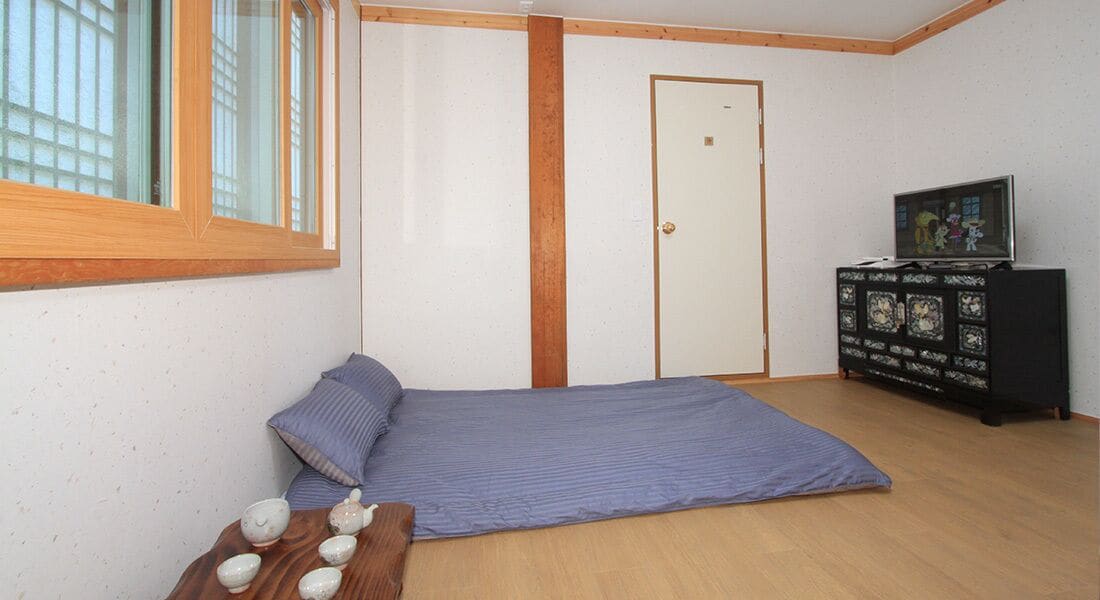 A room with a bed, a wooden cabinet with a TV, and a window.