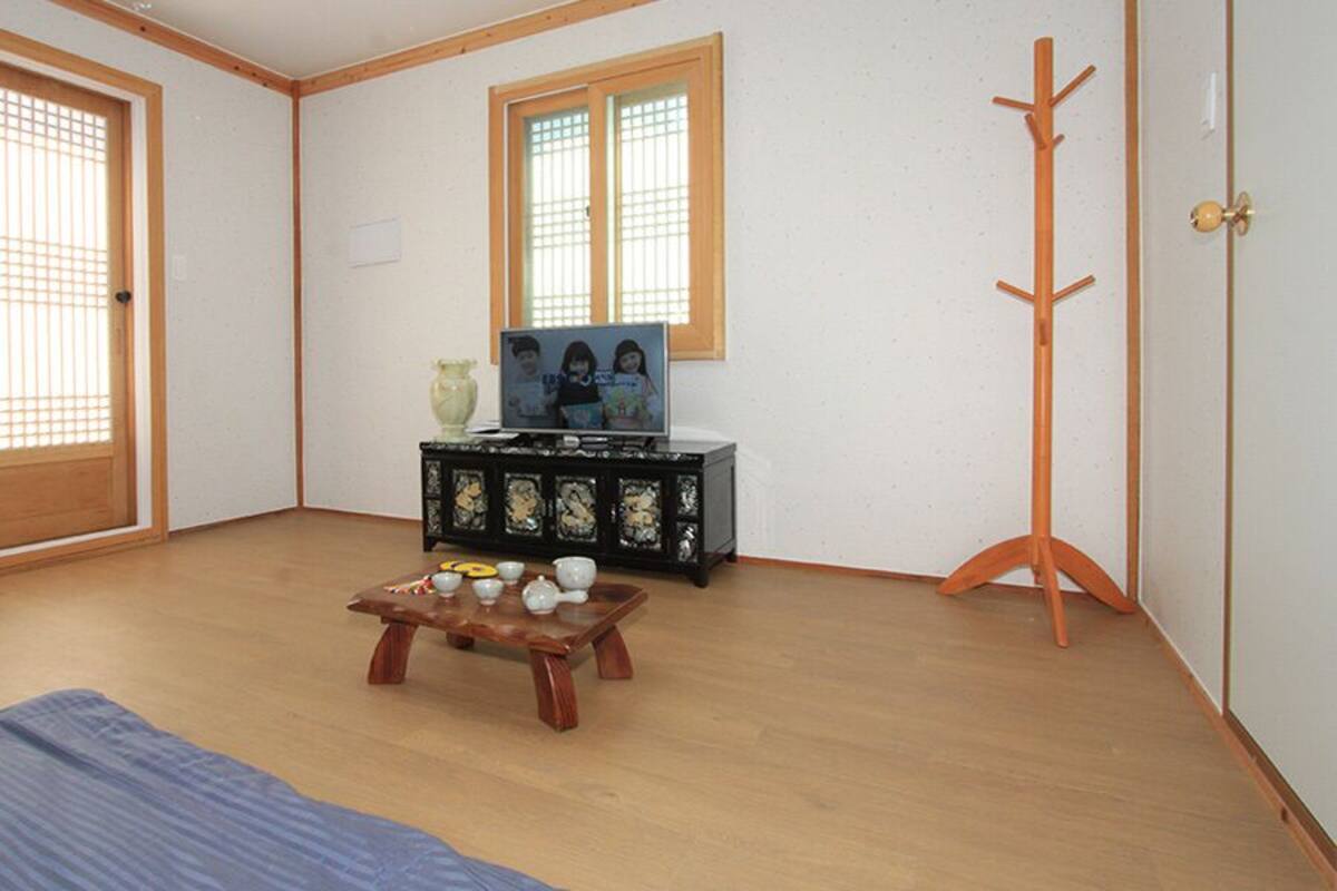 A room with sliding doors, a wooden floor, a small table with cups and a vase, and a coat rack.