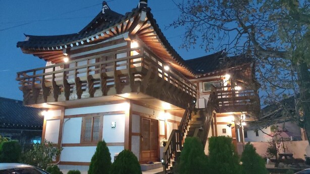 Un bâtiment traditionnel en bois, doté d’un toit à plusieurs niveaux et d’un escalier menant à un étage supérieur.