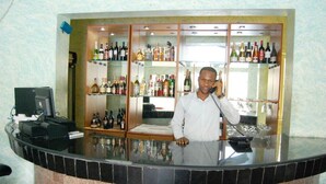 A bar area with a counter, shelves of various bottles, and a computer monitor. - Somitel Hotel And Resort (Port Harcourt)