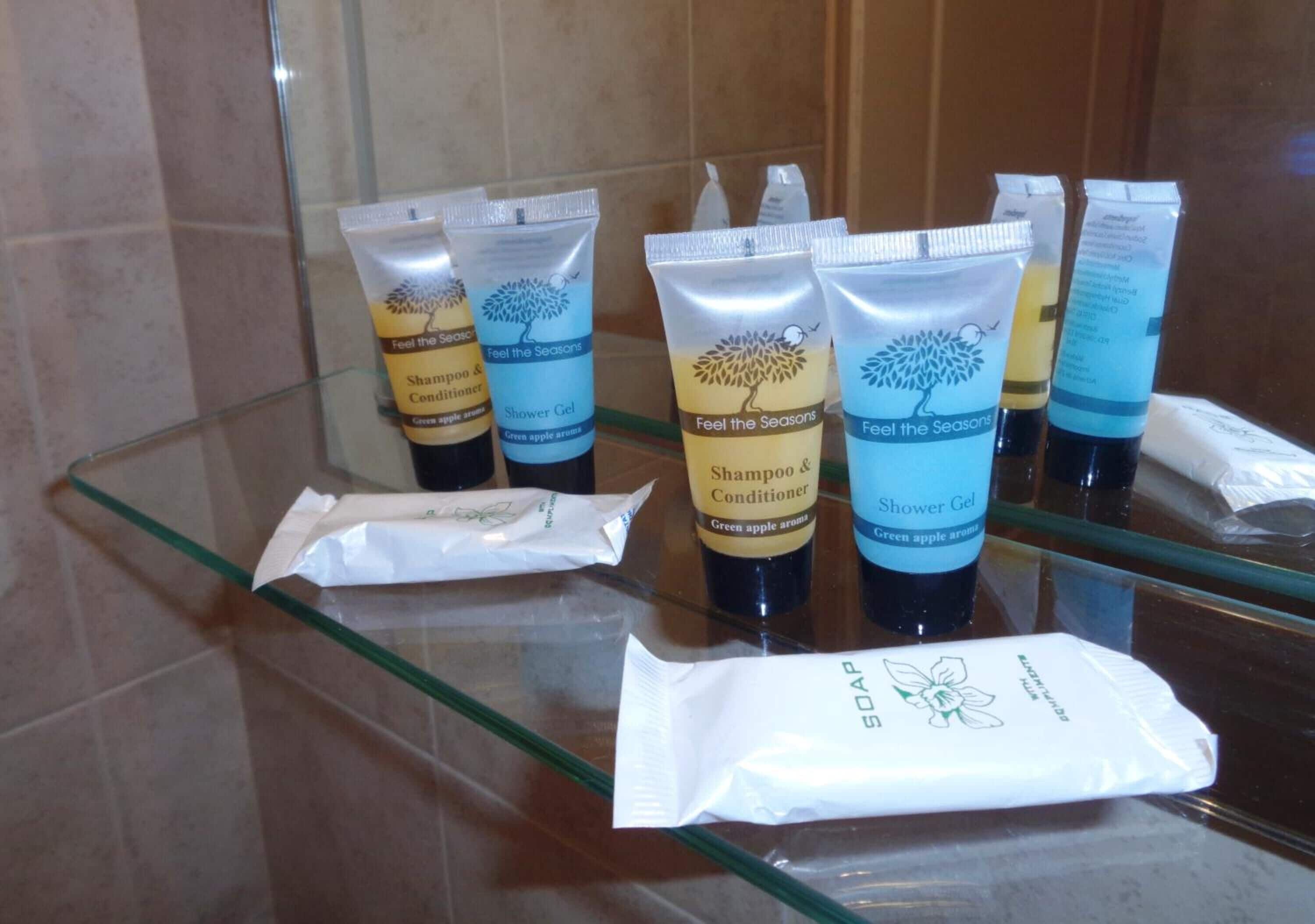 A bathroom counter with several toiletries including shampoo, conditioner, and shower gel.